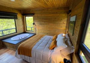a bedroom with a bed and a tub in it at Taipas de Urupema - Vinícola e Pousada Boutique in Urupema