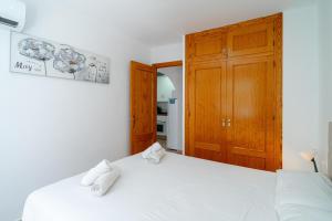 sypialnia z białym łóżkiem i drewnianą szafką w obiekcie Apartmento Caribe Centro Casasol w mieście Nerja