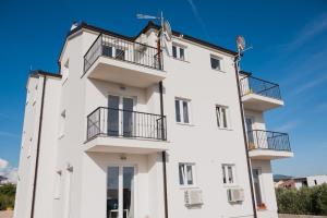 a white building with balconies and a blue sky at M.G Apartments in Brodarica