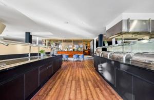a restaurant with a long counter with blue chairs at Leonardo Hotel Hannover Medical Park in Hannover