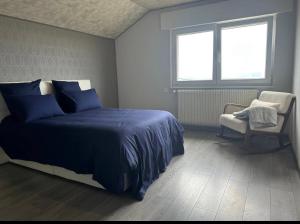 a bedroom with a bed and a chair and two windows at La Maison du Rond-Buisson in Maîche