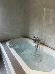 a bath tub filled with water with a faucet at The Retreat in Berrynarbor