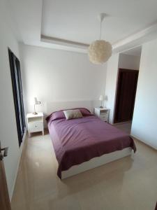 a bedroom with a purple bed and two night stands at Charming appartement in Bouznika in Bouznika +23 photos