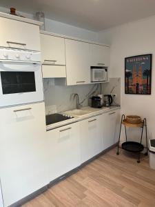 a white kitchen with a sink and a microwave at 4 People Cannes Hyper Centre and Air conditioning in Cannes
