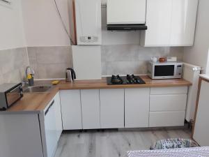 a kitchen with white cabinets and a sink and a microwave at U Józka in Kowary