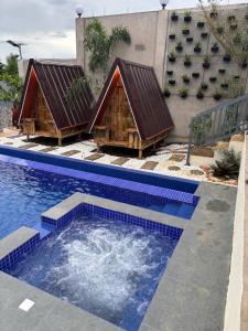 two huts are sitting next to a swimming pool at Hill Top Residence in Sampong
