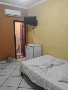 a room with a bed and a television and a bathroom at Pousada Pé na Praia in Rio das Ostras