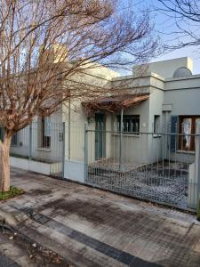 a white building with a fence and a tree at Casa del Cerrito in Tandil