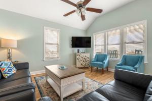 een woonkamer met een bank en stoelen en een plafondventilator bij Nadines Nest in Kitty Hawk