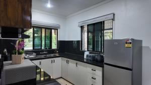 Una cocina con gabinetes blancos y un refrigerador. en Jetsetter's Haven, en Nadi 14 fotos más