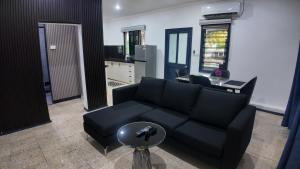 Una sala de estar con un sofá negro y una mesa. en Jetsetter's Haven, en Nadi