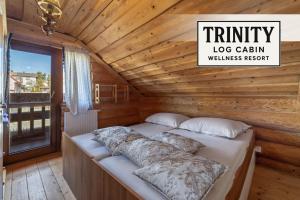 un letto in una baita di tronchi con un cartello che recita "Trinity Log Cabin Wellness" di TRINITY Log Cabin Wellness resort a Štrba