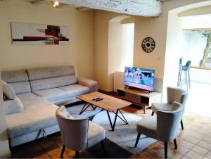 a living room with a couch and a tv at Gîte de l'Église de la Pommeraie in La Pommeraie-sur-Sèvre