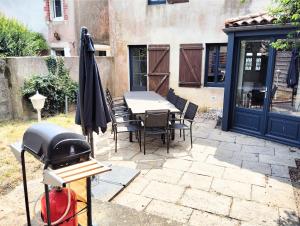 an outdoor grill with a table and chairs and a grill at Gîte de l'Église de la Pommeraie in La Pommeraie-sur-Sèvre