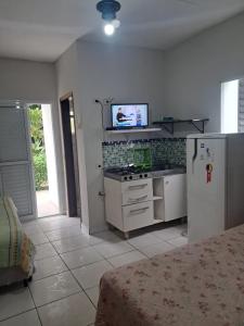 a kitchen with a stove and a tv on the wall at Kitnets & Flats in Ubatuba