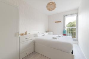a white bedroom with a bed and a window at LE PANORAMIQUE - Face mer - Wifi in Pornichet