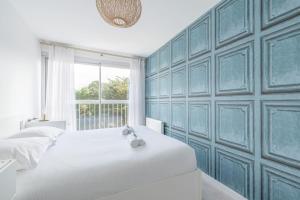 a bedroom with a white bed and a blue wall at LE PANORAMIQUE - Face mer - Wifi in Pornichet