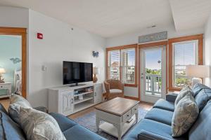 Una sala de estar con un sofá azul y un televisor. en OBX Dream, en Nags Head 21 fotos más