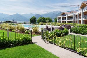 a garden with a fence with mountains in the background at Lago Dorato Luxury Apartments - Lake Como View in Colico