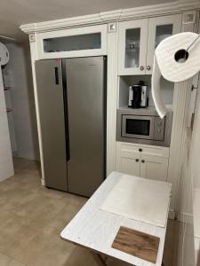 a kitchen with a stainless steel refrigerator and a table at Habitaciones Espacio in Corbera de Alcira