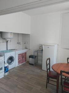 ラヴラネにあるAppartement 2 chambres et salon de massageのキッチン(洗濯機、テーブル付)