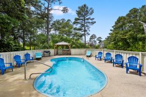 a swimming pool with blue chairs and a gazebo at Ocean Escape in Corolla