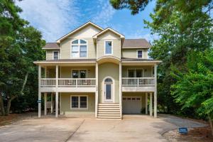 a large yellow house with a large driveway at Ocean Escape in Corolla