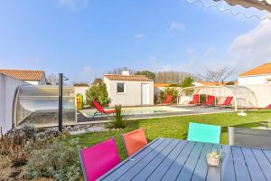 a patio with a table and chairs in a yard at Le Dôme - Piscine - Parking - Jardin in Commequiers