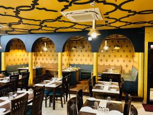 瓦拉纳西Trimrooms Banaras Station的餐厅设有桌椅和黄色天花板 更多20张照片