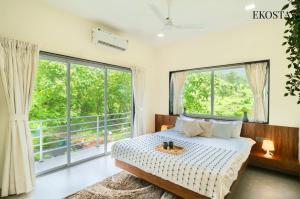 a bedroom with a bed and large windows at EKOSTAY - Alpine Villa in Alibaug