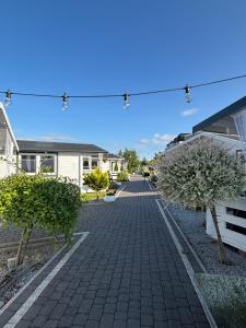 a cobblestone walkway between two houses with trees at Domki LA MER USTKA z własnymi ogródkami- Balia z jacuzzi ,sauna ,rowery, klimatyzacja in Ustka