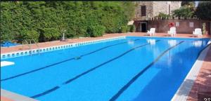 a large blue swimming pool with two white chairs at Castello Bellariva with Swimming Pool and Tennis Court in Cavo