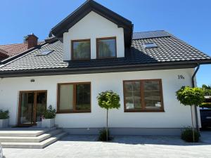 a white house with a black roof at Apartamenty Zamojska in Zwierzyniec