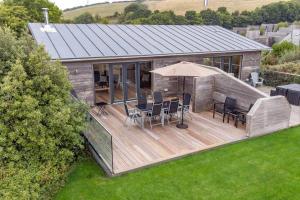 a house with a deck with chairs and an umbrella at House 35 in Looe