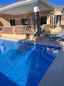 einen Pool mit blauem Wasser vor einem Haus in der Unterkunft Casa la Riviera del Sol in Mijas Costa