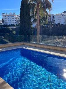 ein großer blauer Pool mit Palmen und Gebäuden in der Unterkunft Casa la Riviera del Sol in Mijas Costa