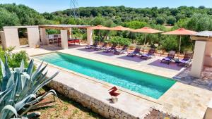 una piscina con lettini e ombrelloni di Corte Artemide a Ostuni Altre 74 foto