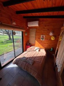a bedroom with a bed in a wooden cabin at Confortable cabaña con parrilla in Chascomús