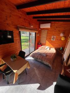 a bedroom in a log cabin with a bed and a table at Confortable cabaña con parrilla in Chascomús