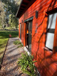 a red brick building with a door and a window at Confortable cabaña con parrilla in Chascomús