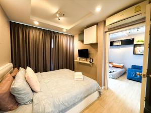 Un pequeño dormitorio con una cama y un televisor. en Finn Room Plus 38 sqm & The Patio by BHB, en Bangsaen Sai 1