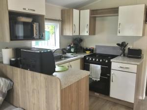 a kitchen with white cabinets and a black stove at 38 The Green in Porthmadog