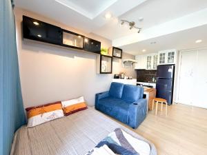 Una sala de estar con un sofá azul y una cocina. en Finn Room Plus 38 sqm & The Patio by BHB, en Bangsaen Sai 1