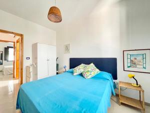 a bedroom with a blue bed and a bathroom at CASA TYCHE - grazioso alloggio a Torre dell' Orso in Torre dell'Orso