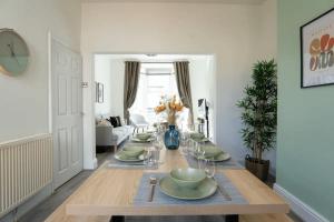a dining room with a table with green dishes on it at 3 Bed House 9 mins walk to Anfield Sleeps 7 in Liverpool