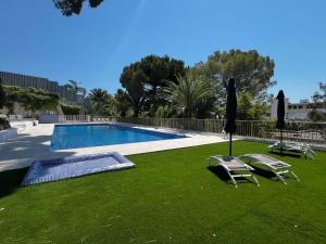 a swimming pool with two lawn chairs and an umbrella at Villa Estérel Large Studio with Terrace in Cannes