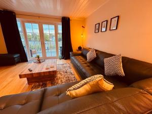 a living room with a leather couch and a coffee table at Barneys Retreat - Lakeside Getaway in South Cerney