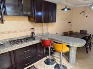 Una cocina con encimera, estufa y sillas. en Appartement confort et lumineux, en Agadir 28 fotos más