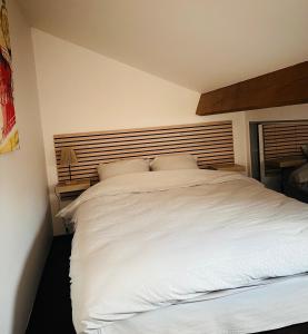 a bedroom with a white bed with a wooden headboard at Petite maison indépendante à 20min de Paris in Bonneuil-sur-Marne