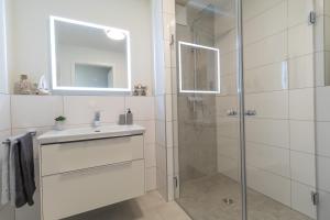 a white bathroom with a sink and a shower at Herz von Kellenhusen 8 - mit Sauna und Balkon, nur 300m vom Strand entfernt in Kellenhusen +27 photos